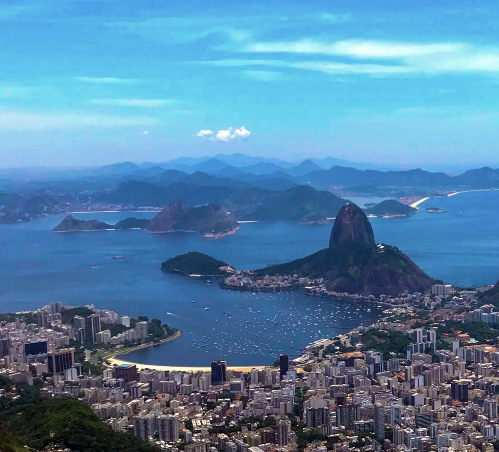 Vista panorâmica da Baía de Guanabara a partir do Cristo Redentor (situado dentro do Parque Nacional da Tijuca), com o Pão de Açúcar em destaque e a cidade do Rio de Janeiro ao fundo.